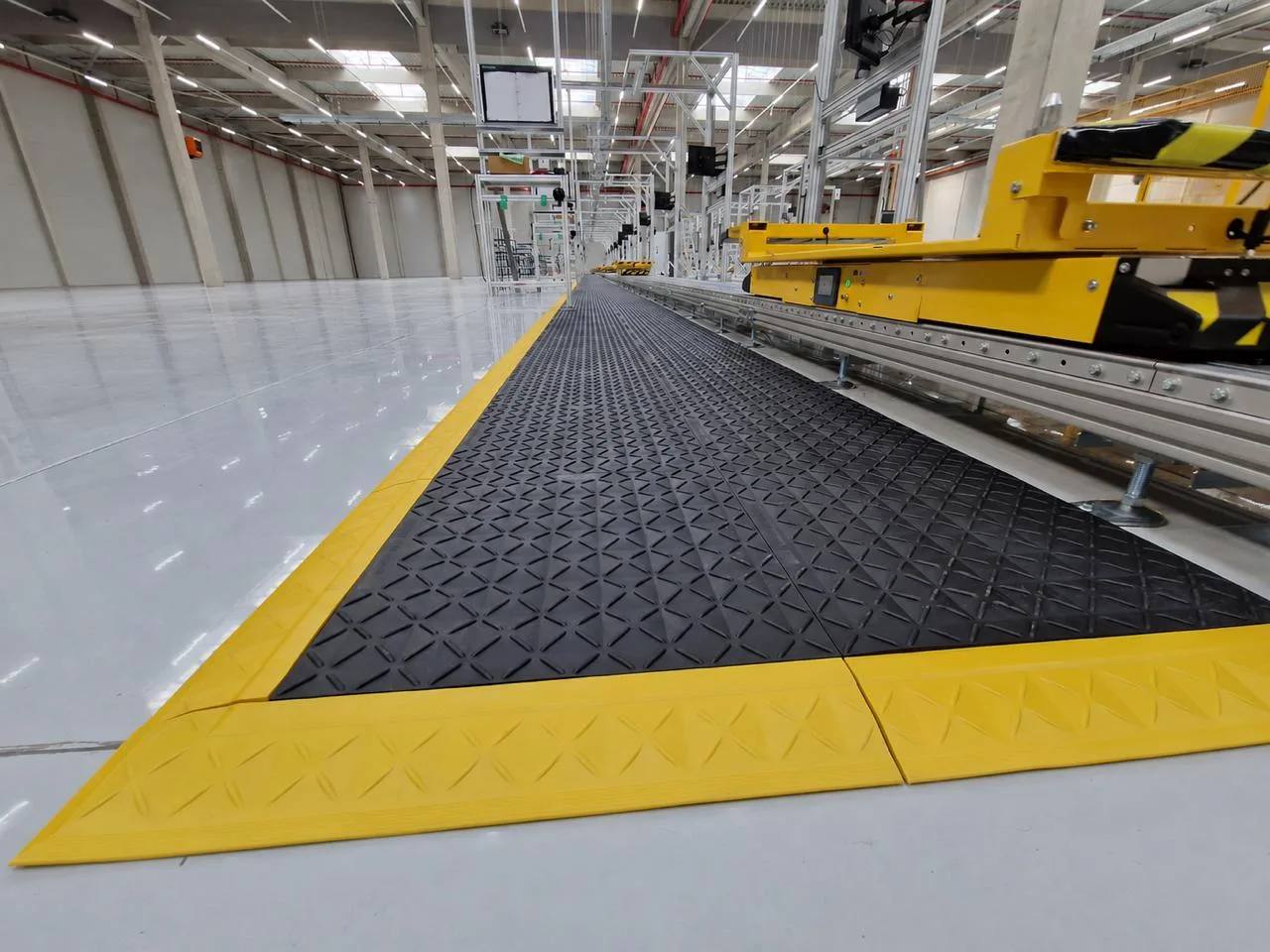A long run of black and yellow anti-fatigue matting along a production line.